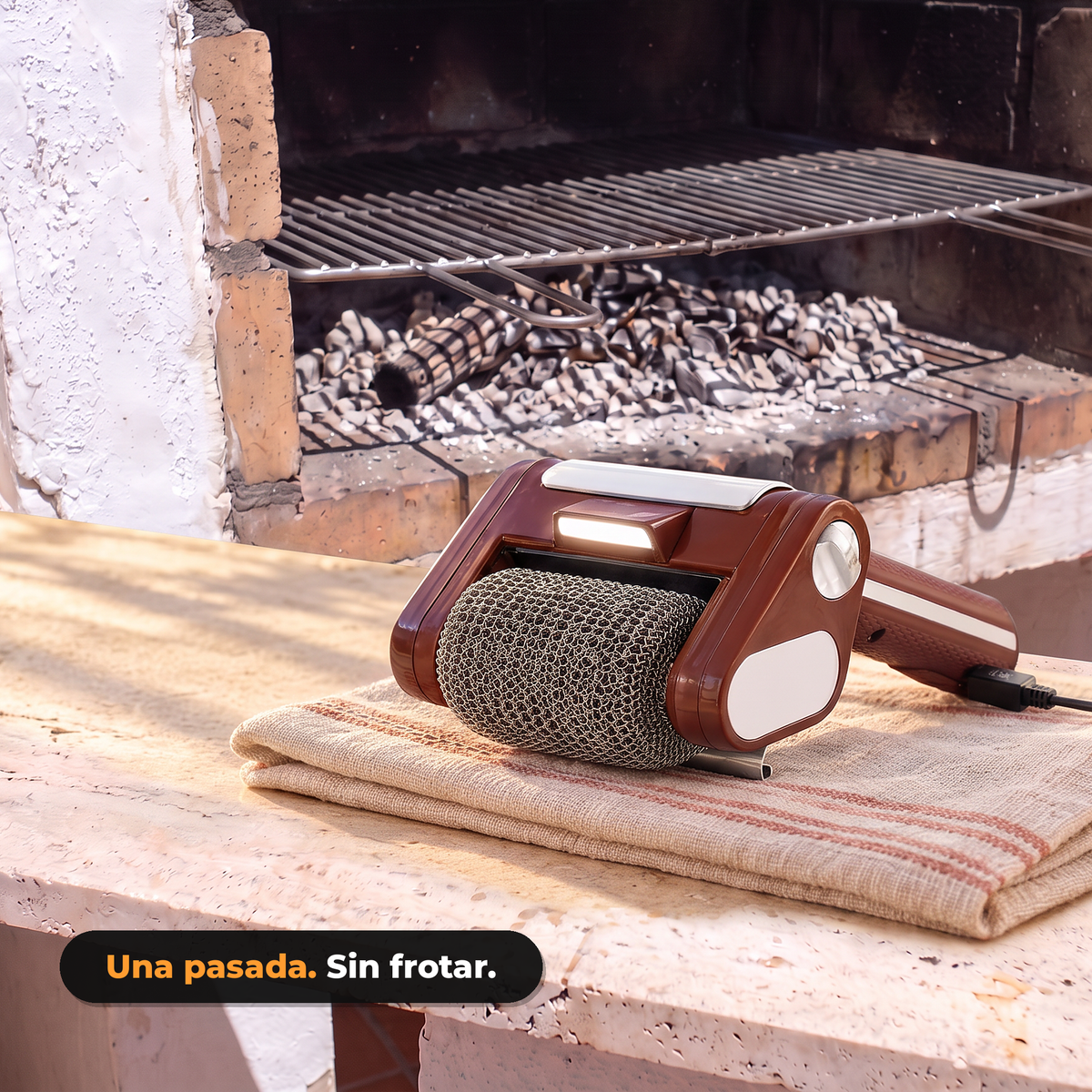 Cepillo eléctrico para barbacoa LimpiaBrasa sobre una repisa junto a una barbacoa de obra